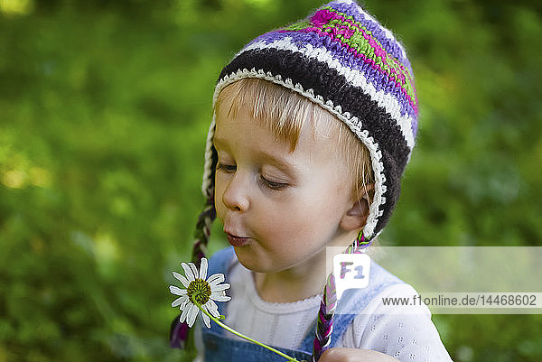 Bildnis eines kleinen Mädchens mit gestrickter Mütze und wehender Blume