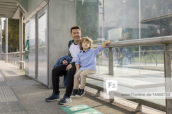 Vater und Sohn sitzen an der Straßenbahnhaltestelle in der Stadt