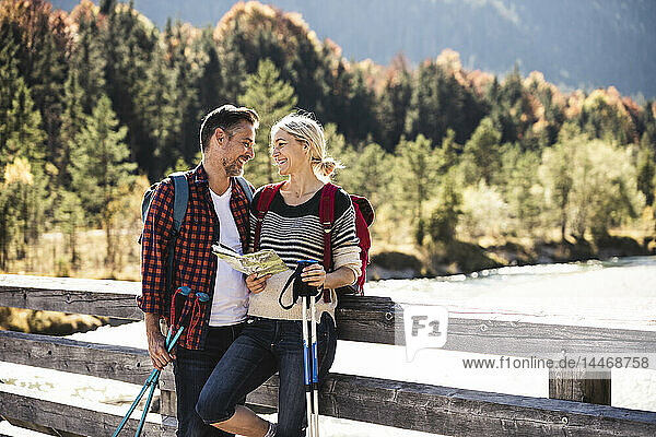 Österreich  Alpen  glückliches Paar auf einer Wanderung mit Karte auf einer Brücke