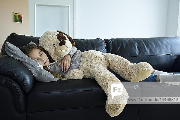 Girl relaxing on couch with oversized soft toy