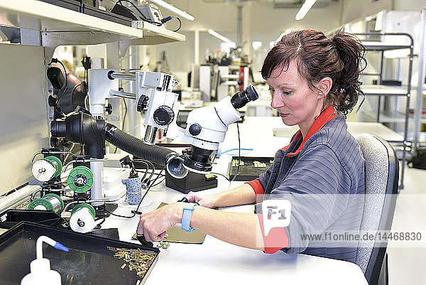 Frau  die an der Qualitätskontrolle bei der Herstellung von Leiterplatten für die Elektronikindustrie arbeitet