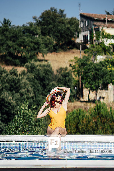Hübsche Frau im Badeanzug beim Sonnenbaden am Pool