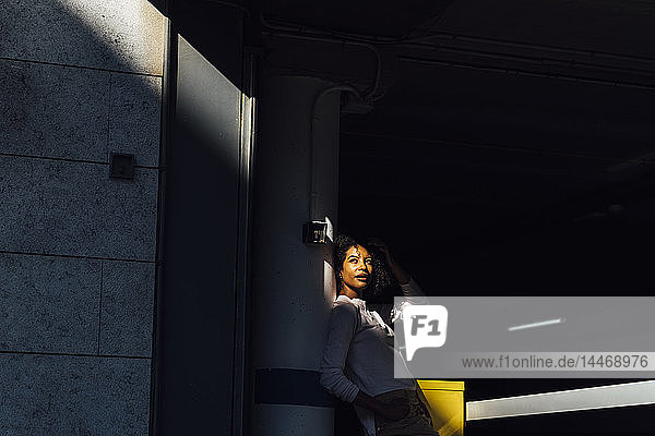 Junge lockere Geschäftsfrau auf dem Parkplatz  Sonnenlicht und Schatten