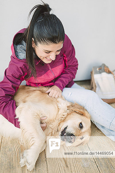 Glückliche junge Frau streichelt und spielt mit ihrem Golden Retriever-Hund
