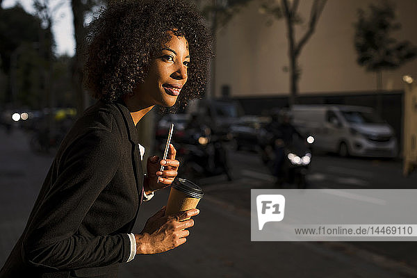 Porträt einer Geschäftsfrau mit Kaffee zum Mitnehmen und Handy in der Abenddämmerung wartend