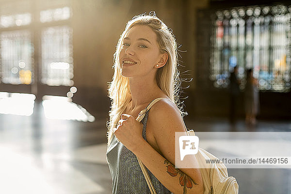 Porträt einer lächelnden jungen Frau mit einer Tätowierung im Gegenlicht