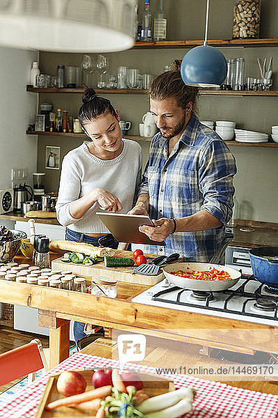 Young couple preparing spaghetti together  using online recipe