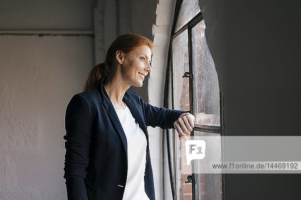 Lächelnde Geschäftsfrau schaut aus dem Fenster