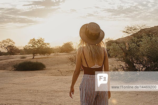 Namibia  Spitzkoppe  rear view of woman with hat at sunset