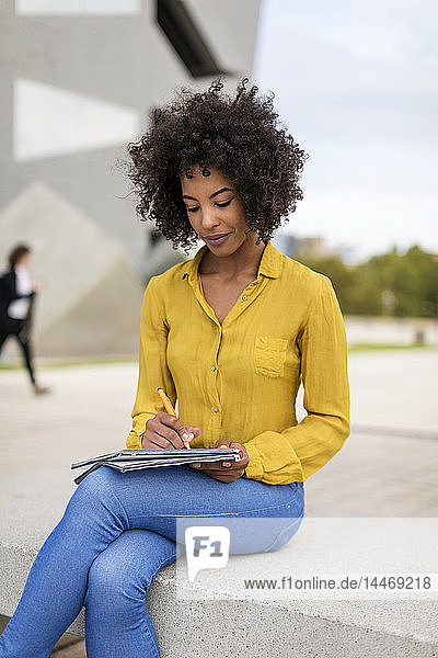 Woman sitting on bench taking notes