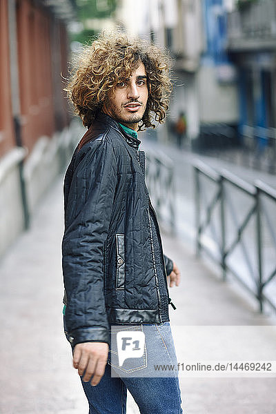 Spain  Granada  portrait of young man with curly hair walking on pavement