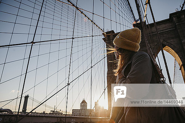 USA  New York  New York City  Touristin auf der Brooklyn Bridge bei Sonnenaufgang