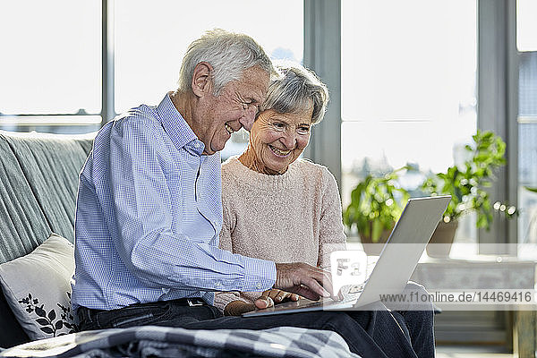 Älteres Ehepaar sitzt zusammen auf der Couch mit Laptop