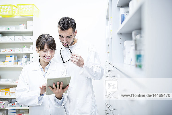 Two pharmacists using tablet in pharmacy