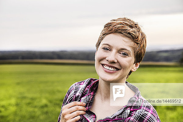 Porträt einer lächelnden Frau im Pyjama in ländlicher Landschaft