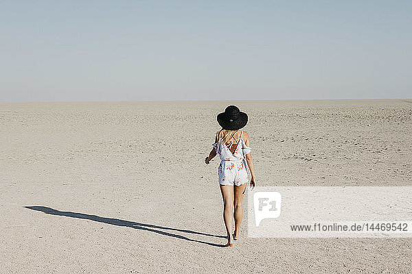 Frau mit schwarzem Hut  die in der Wüste spazieren geht