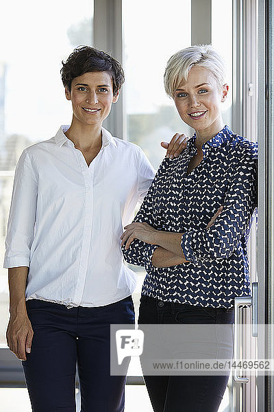 Portrait of two smiling businesswomen at the window in office
