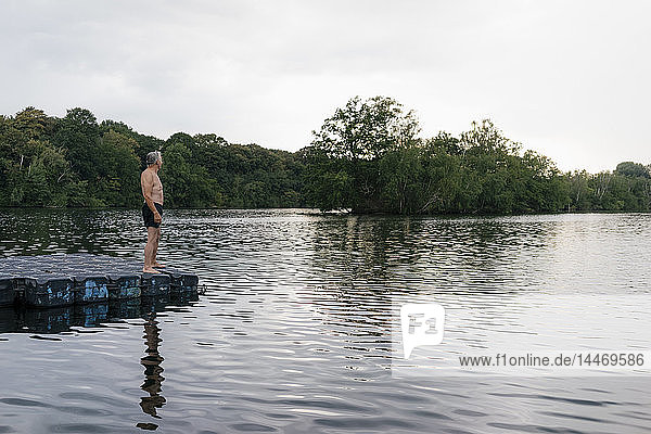 Senior man standing on raft in a lake