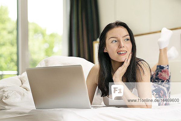 Young woman lying bed  using laptop in the morning
