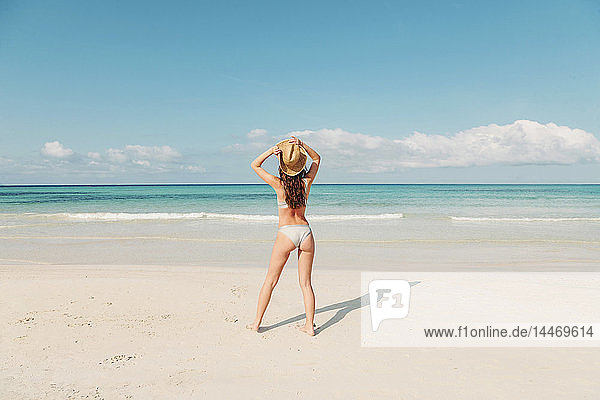 Spanien  Mallorca  Rückansicht einer jungen Frau im Urlaub am Strand stehend