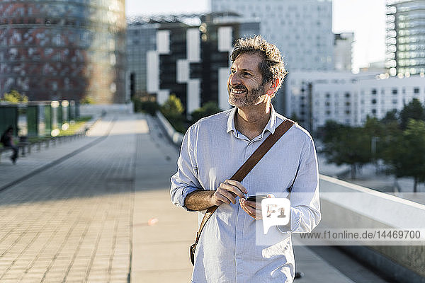 Smiling mature man with cell phone in the city