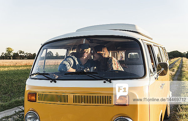 Glückliches Paar sitzt in seinem Wohnwagen und küsst sich