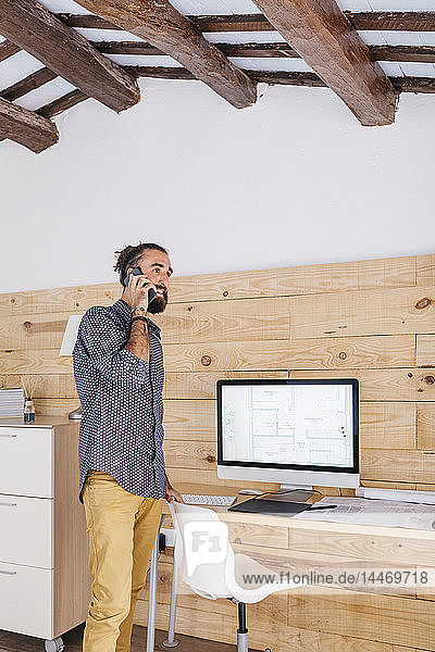 Young architect in office at home talking on the phone