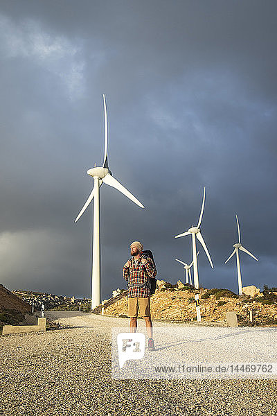 Spanien  Andalusien  Tarifa  Mann auf einer Wanderung auf einem Feldweg stehend mit Windturbinen im Hintergrund