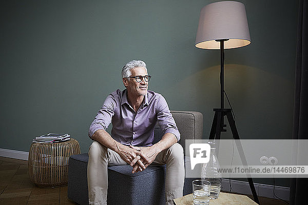 Mature man sitting on armchair at home