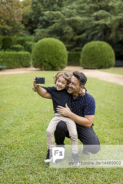 Happy father and son on taking a selfie in park