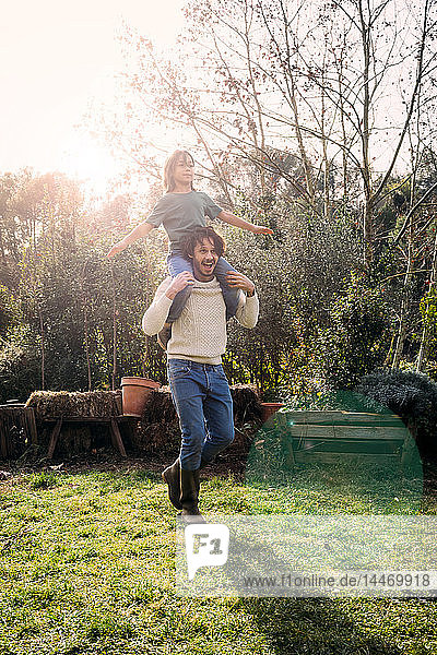 Vater spielt mit seinem Sohn und trägt ihn huckepack in einem Garten