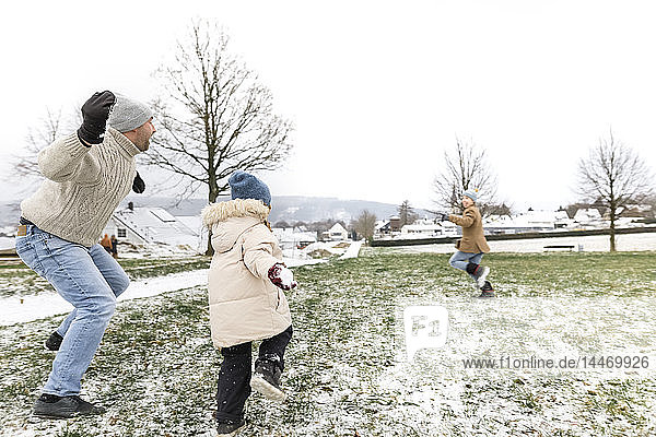 Father and two children having a snowball fight