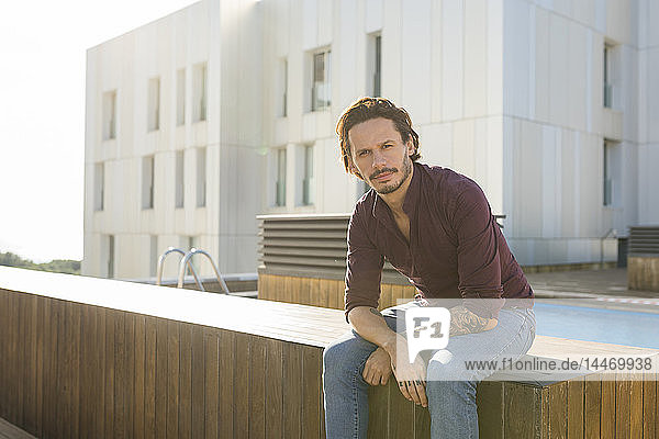 Mann sitzt auf einer Dachterrasse