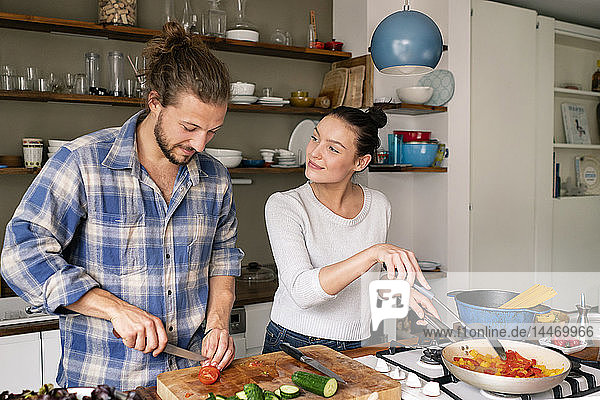 Junges Paar bereitet gemeinsam Essen zu  probiert Spaghetti