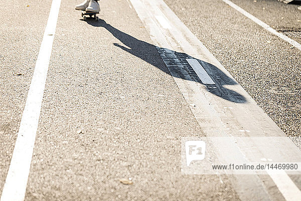 Schatten eines Mannes beim Skateboarden auf dem Radweg