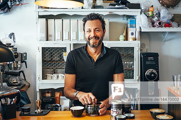 Portrait of smiling barista at the counter of a coffee shop
