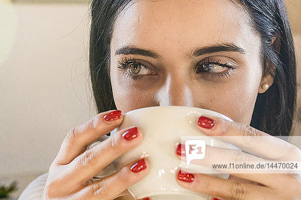 Nahaufnahme-Porträt einer schönen jungen Frau  die eine Tasse Kaffee trinkt
