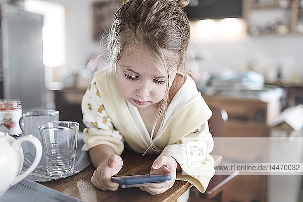 Kleines Mädchen mit Smartphone in der Küche