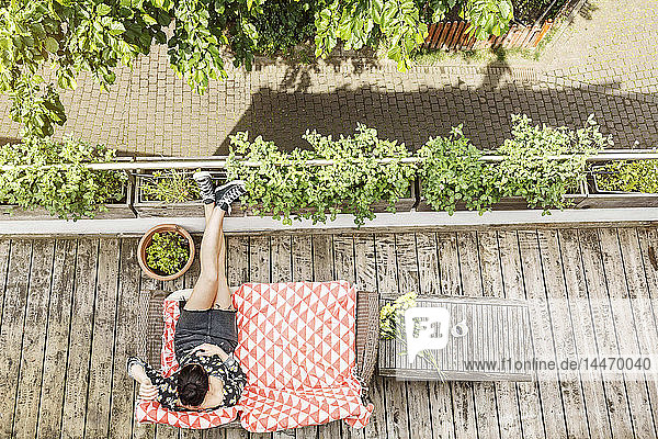 Junge Frau entspannt sich im Sommer auf ihrem Balkon