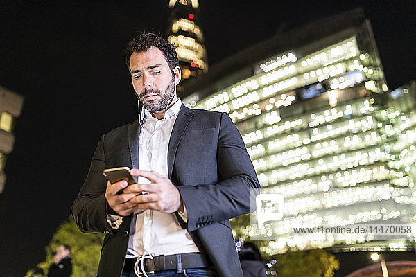 Großbritannien  London  Geschäftsmann unterwegs  der nachts beim Pendeln sein Telefon überprüft