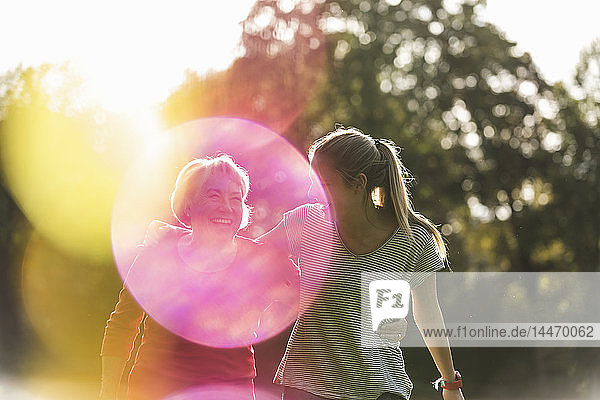 Fitnessgroßmutter und Enkelin gehen mit umarmenden Armen durch den Park