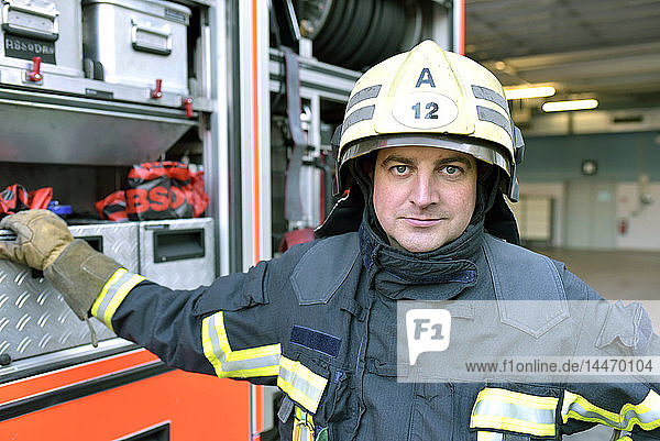 Porträt eines selbstbewussten Feuerwehrmannes vor dem Feuerwehrauto