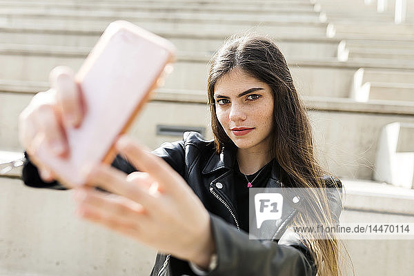 Porträt einer jungen Frau auf einer Treppe  die ein Selfie nimmt