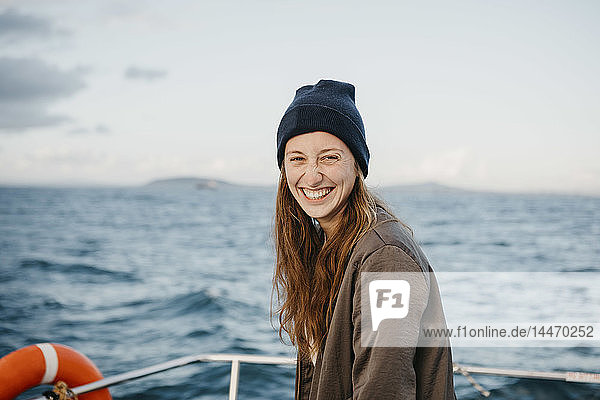 Südafrika  junge Frau mit Wollmütze lächelt während einer Bootsfahrt bei Sonnenuntergang