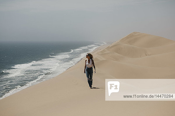 Namibia  Walvis Bay  Namib-Naukluft-Nationalpark  Sandwich-Hafen  Frau wandert in Dünenlandschaft am Meer