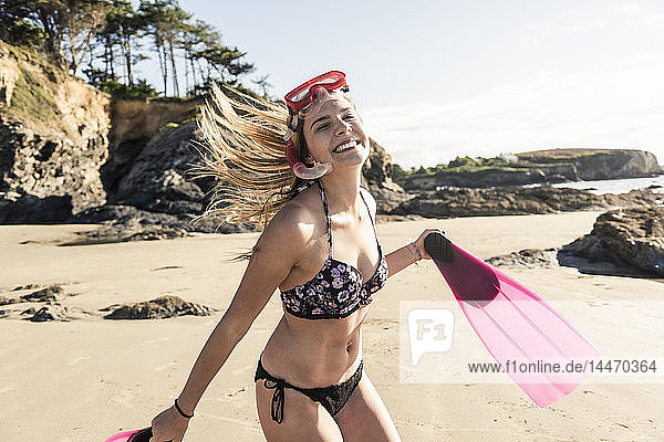 Happy young woman with snorkelling equipment  running on the beach
