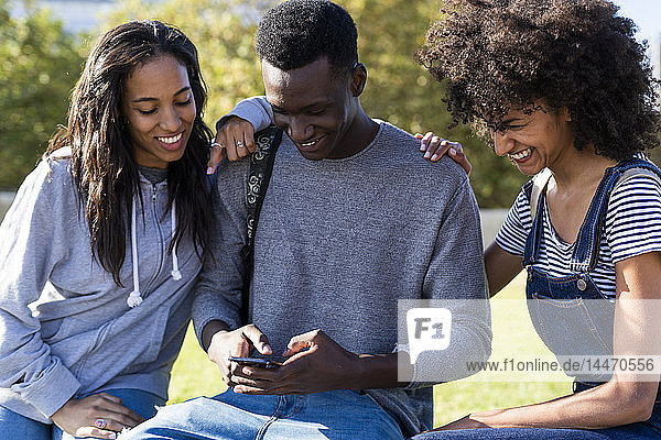 Drei Freunde verbringen Zeit in der Stadt und benutzen ein Smartphone