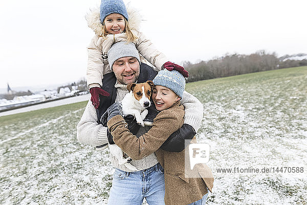 Happy father with two children and dog in winter landscape