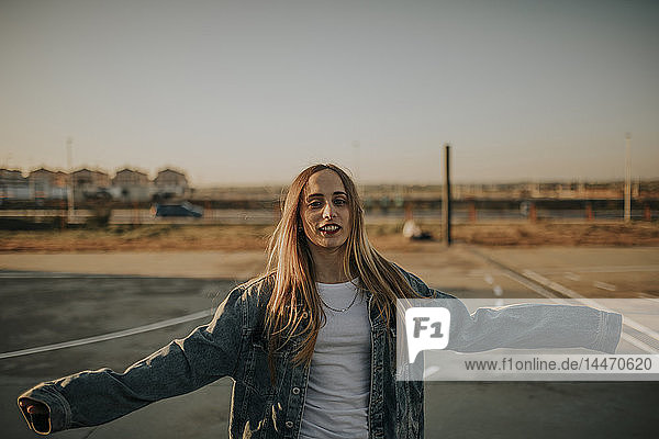 Porträt einer lächelnden jungen Frau mit ausgestreckten Armen im Freien