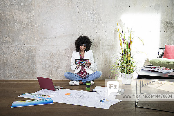 Businesswoman sitting on the floor in a loft using tablet